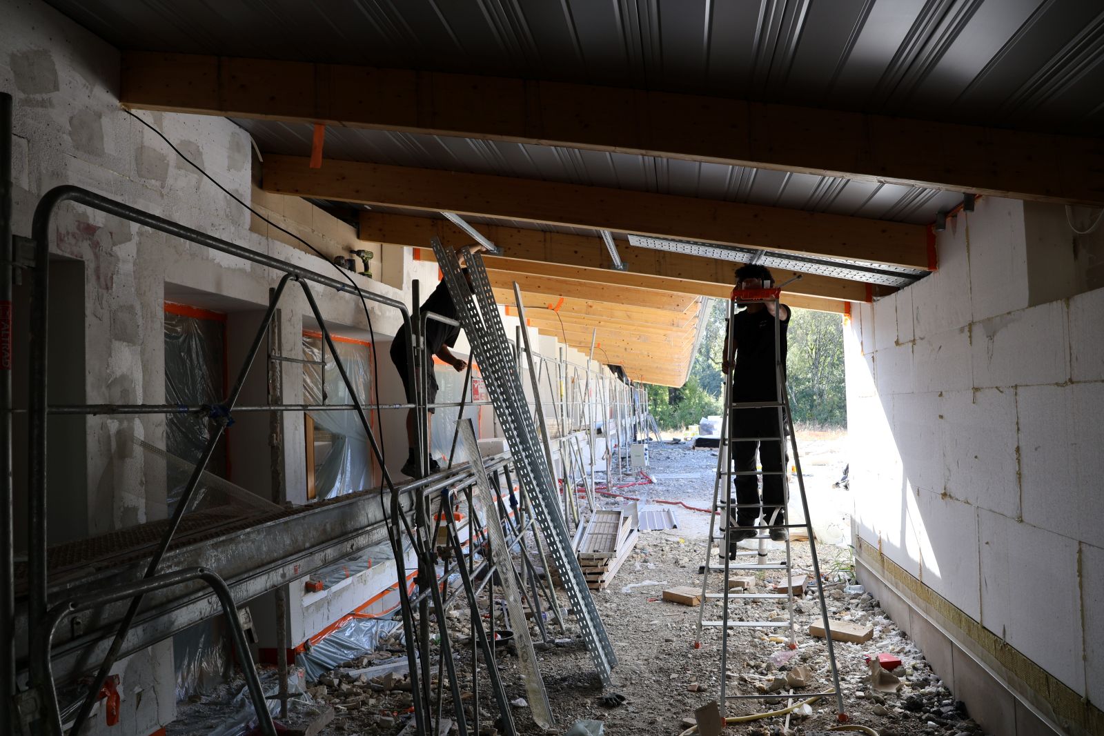 Travaux en cours sous le préau du groupement scolaire Villemur-sur-Tarn, avec ouvriers installant des éléments de structure et d’électricité, octobre 2025.