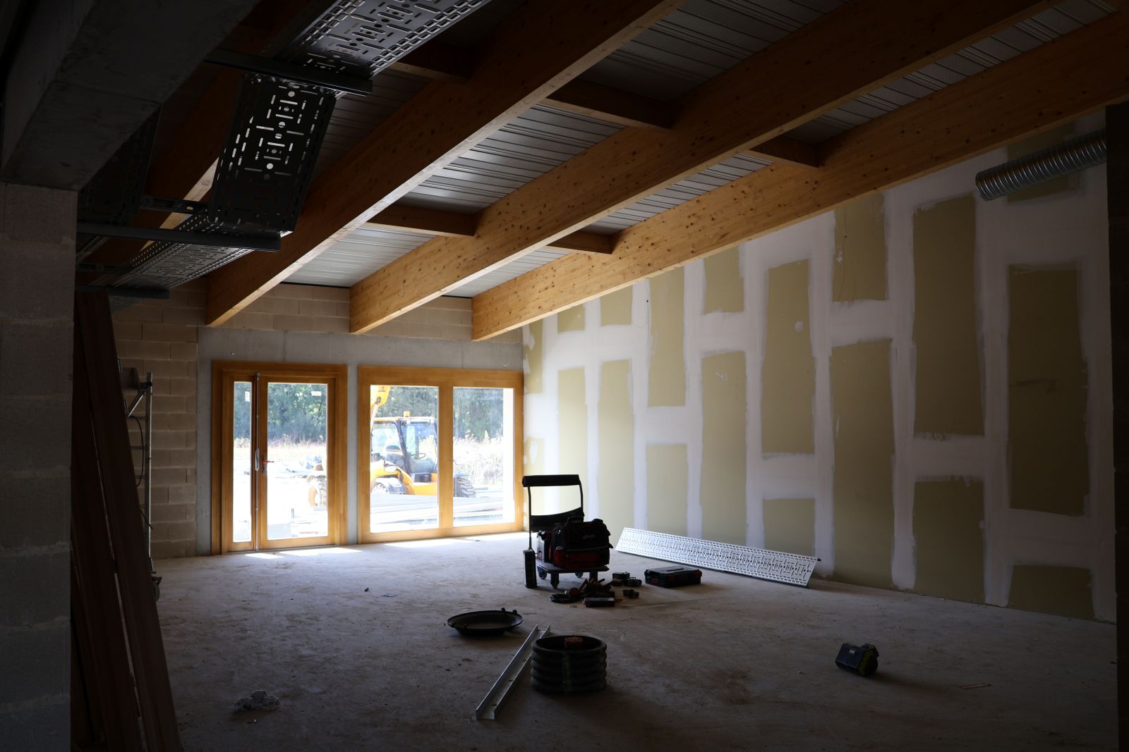 Intérieur du groupement scolaire Villemur-sur-Tarn en cours d’aménagement, avec cloisons montées, plafonds apparents et matériel de chantier au sol, octobre 2025.