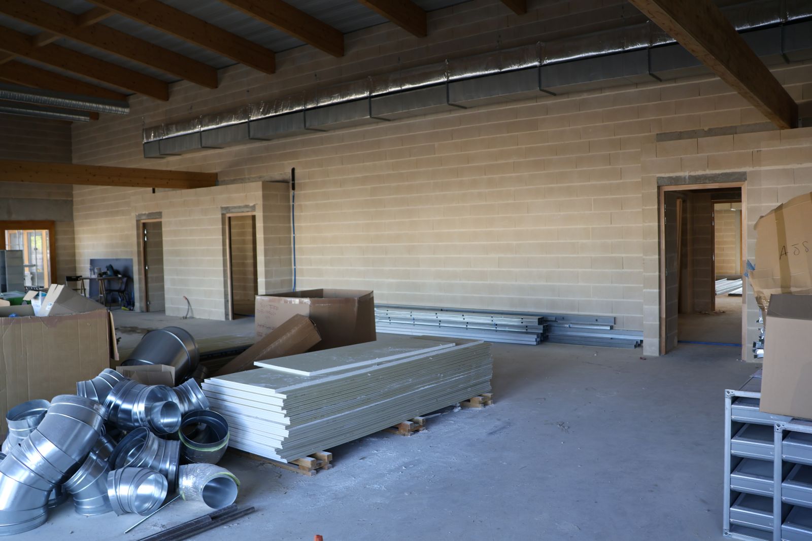 Intérieur du groupement scolaire Villemur-sur-Tarn en chantier, avec matériaux de construction et gaines de ventilation en cours d’installation, octobre 2025.