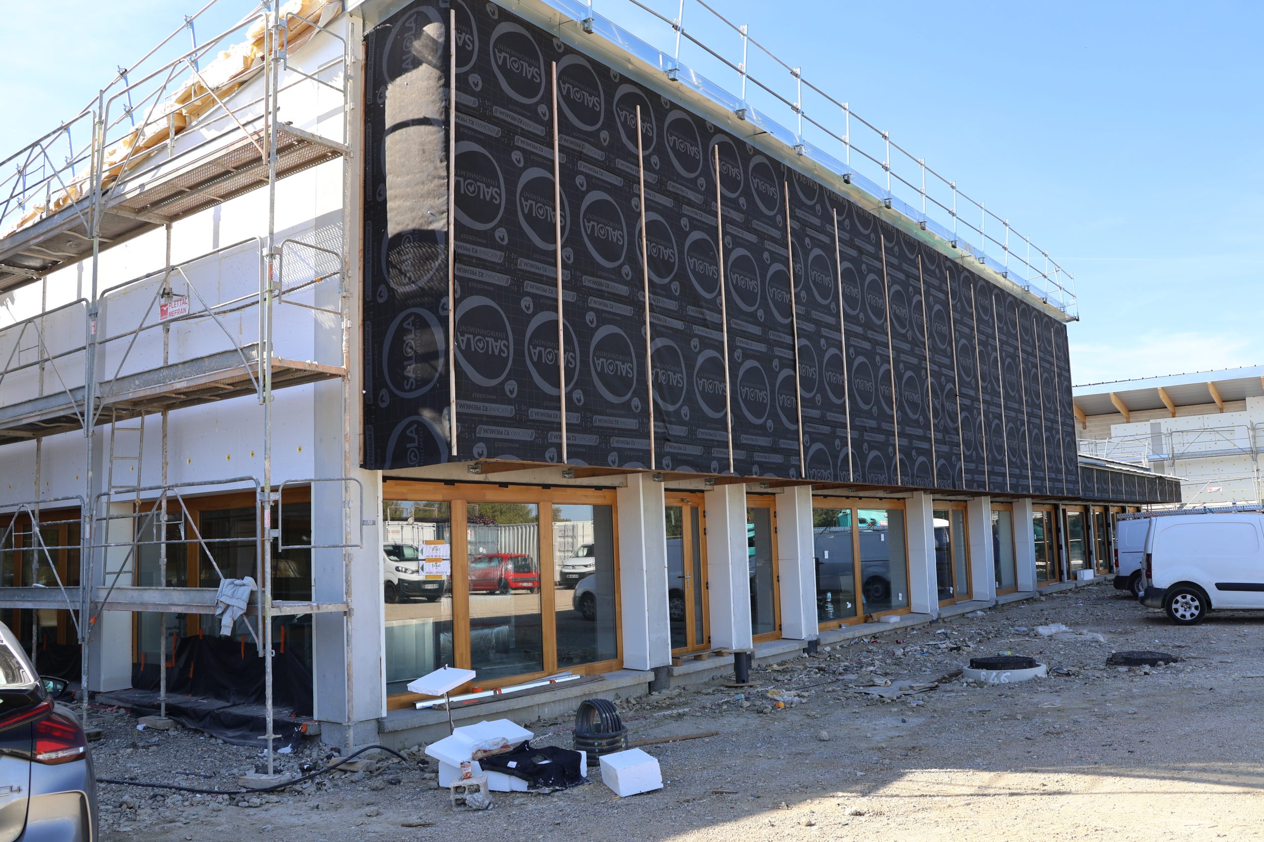 Façade du groupement scolaire Villemur-sur-Tarn en cours d’isolation et de bardage, avec échafaudages et menuiseries déjà installées, octobre 2025.