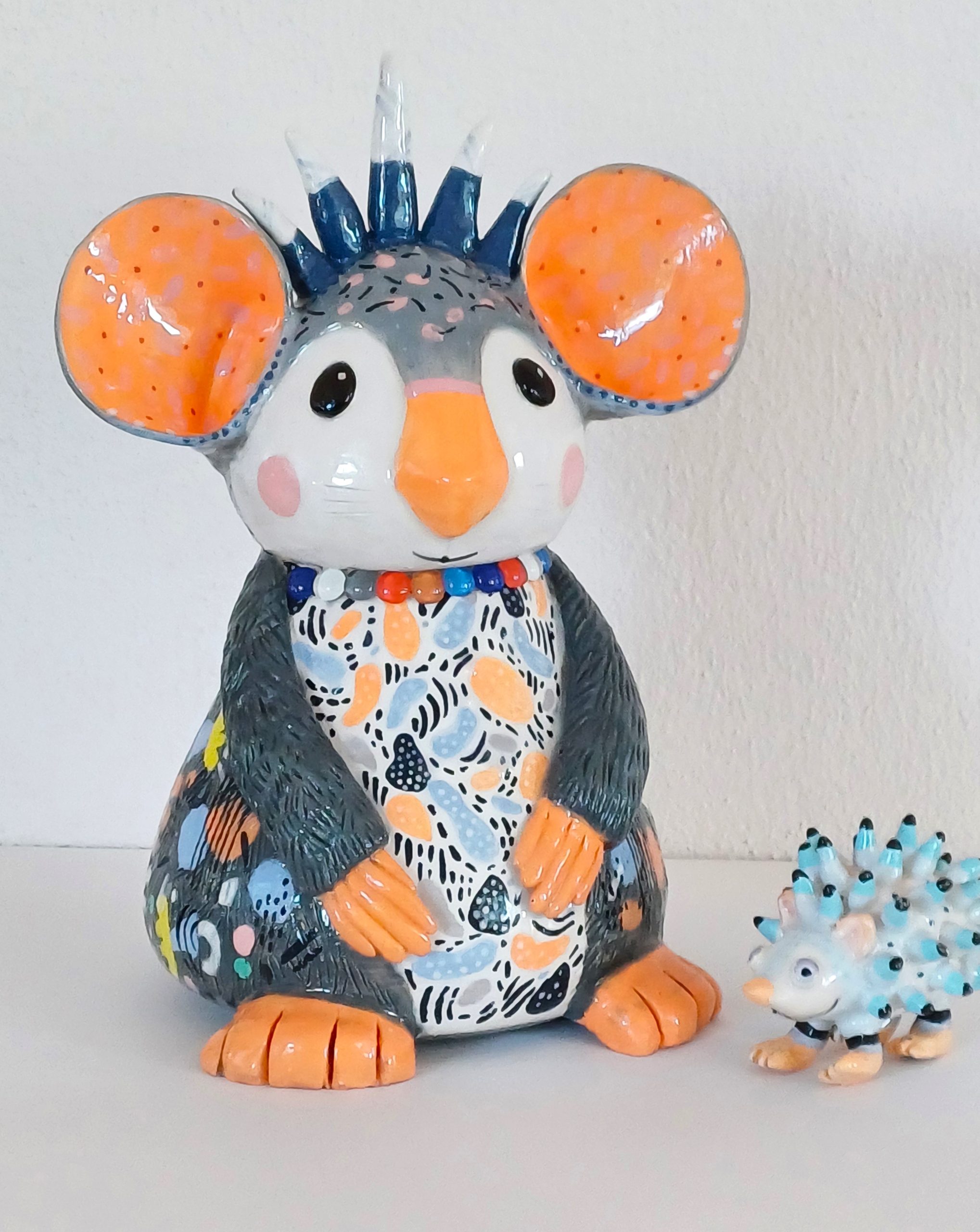 Sculpture colorée représentant un koala et un hérisson en céramique, réalisés dans un style ludique et décoratif.